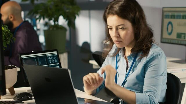 Cheerful worker feeling good over positive business accomplishment. Smiling woman in office celebrating achievement while looking at laptop screen, excited by successfully completed tasks, camera A