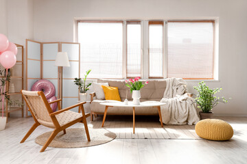 Interior of light living room decorated for Women's Day with sofa, armchair and table