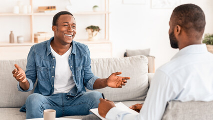 Successful Therapy. Cheerful black man talking to psychologist on meeting at his office, sharing his progress with doctor