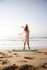 A ballerina in a light dress balances on a surfboard, her posture full of grace and mindfulness. A symbolic visual of inner peace, artistic freedom, and movement as meditation. 