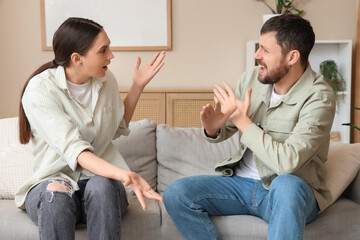 Angry young couple quarreling on sofa at home