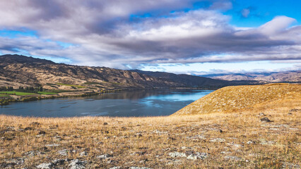 Fototapeta premium Beautiful lake surrounded by hills and mountains cromwell new zealand autumn landscape clear day beautiful scenery
