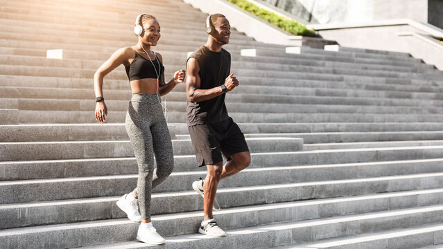 Active Black Athlete Couple Running Outdoors On Steps In Urban Park, Copy Space - Powered by Adobe