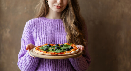 Young caucasian female holding freshly baked spinach pizza in cozy setting