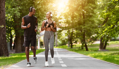 Obraz premium Relationship Goals. Black Couple Jogging Together In Morning Park, Enjoying Training Outdoors, Copy Space