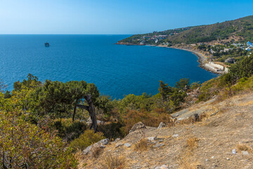 a magnificent view of the Crimean coast. From above, a panorama of the curved coastline, covered with sparse vegetation, rocks and junipers, opens up 