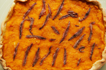 Orange pumpkin pie with anchovies. Top view