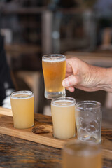 Hand lifting a glass of beer from a tasting paddle in Margaret River, Western Australia