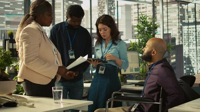Employee with paraplegia and colleagues in inclusive office brainstorming, reviewing financial charts, analyzing KPIs. Person with paraplegia and team coworkers colleagues comparing data, camera B