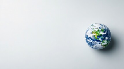 Fototapeta premium A small globe model resting on a minimalist white surface, showcasing continents and oceans, and symbolizing global unity and environmental awareness.