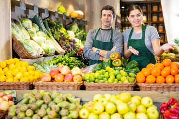 Portrait of positive friendly shop assistants in apron in the grocery section of the supermarket