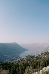 Obraz premium View from the mountain to the valley of the Bay of Kotor surrounded by mountains in a light haze. Montenegro