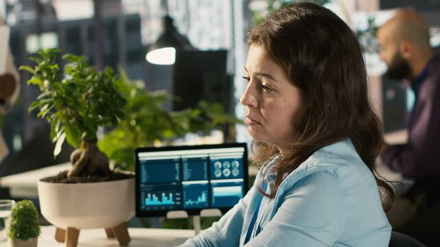 Stressed worker in office sighs, burdened by too many documents to review. Tired employee at work feeling overworked while analyzing business performance metrics, camera A