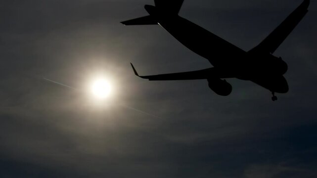 Silhouetted airplanes landing during golden sunset, revealing dramatic backlighting with soft airport horizon and diffused evening skyline in graceful slow motion