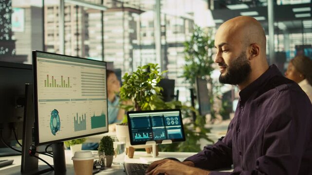Startup staff member working to hit key performance targets for revenue, profitability and operational efficiency. Employee at computer desk doing research analysis, camera B close up