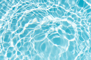 Blue water with ripples on the surface. Defocus blurred transparent blue colored clear calm water surface texture with splashes and bubbles. Water waves with shining pattern texture background.