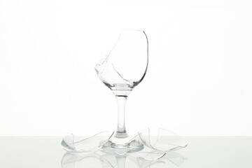Pieces of broken wine glass on table against white background