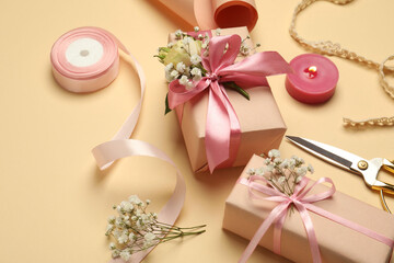 Florist. Boxes, flowers, ribbon, burning candle and scissors on beige background