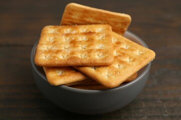 Tasty salty crackers on wooden table, closeup
