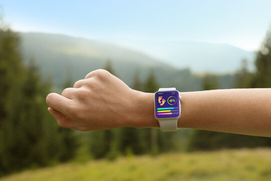 Woman checking smart watch with step counting app in wilderness, closeup
