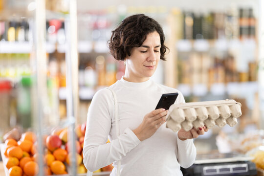 Adult woman buyer scanning qr code for packaged eggs in grocery store