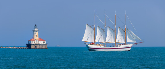 A beautiful white sail tour boat and Chicago harbor lighthouse in the lake Michigan