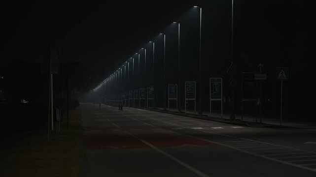 Deserted street lit by rows of lamps near Jarun lake at night in Zagreb Croatia