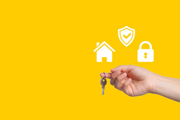 Hand holding keys with icons representing home security and protection in vibrant yellow