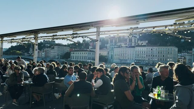 Outdoor cafe with people enjoying drinks by Soane river in Lyon, France on a sunny day