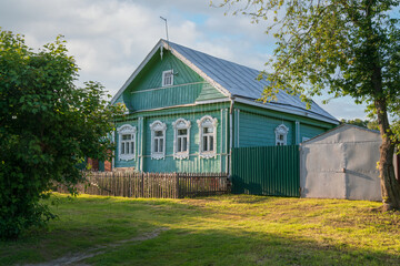 Russian traditional wooden house decorated with house carvings and a front garden on a sunny summer...