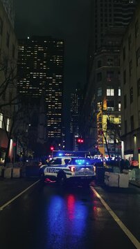 Nighttime police car securing urban street in Manhattan downtown of New York City, vertical video