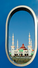 Frame in frame view. A majestic mosque architecture building in the city square exposed against the morning sunlight viewed through the hole