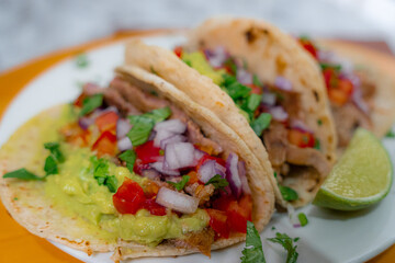 Close-up photo of traditional tacos with avocado on a wooden platform