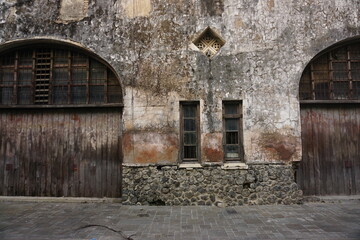 Fototapeta premium Old weathered building facade, wood doors, stone base, urban setting, historical architecture