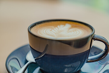 Closeup photo of cappuccino coffee in blue ceramic cups with a spoon on a wooden table