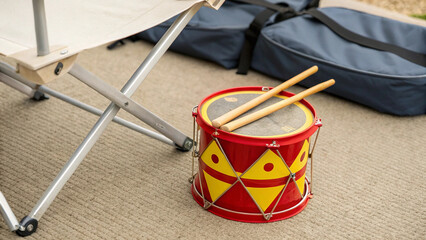 toy-drum-and-sticks-set-placed-beside-folded-camp