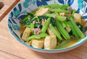 Stir-fried Chinese mustard green with minced pork and fried tofu, homemade Asian healthy menu, close-up image with natural light.