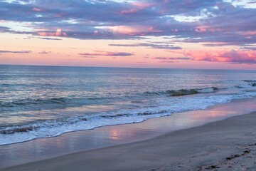 Obraz premium Tranquil Beach Scene With Soft Waves And Pink Clouds At Sunrise