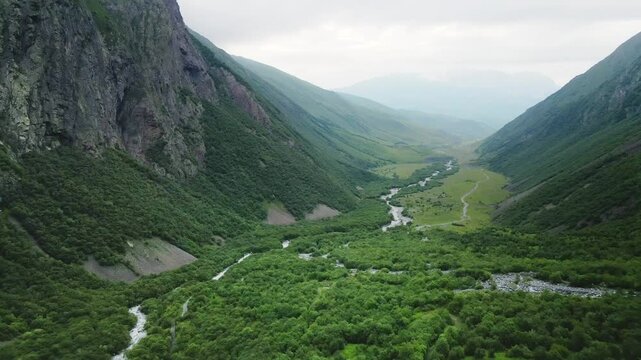 Green trees and river in the mountain gorge at foggy day. Aerial view. Beautiful summer landscape. Digor Gorge in North Ossetia, Caucasus, Russia. 
