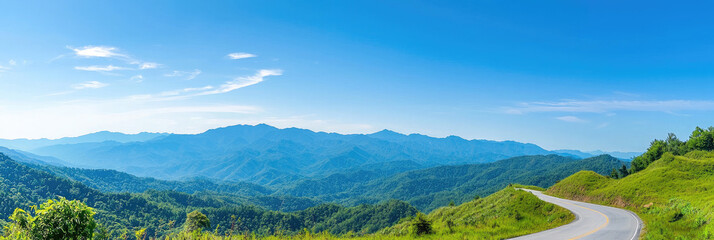 A winding mountain road leading to breathtaking panoramic views under a vibrant summer sky with lush green hillsides and a clear blue horizon.