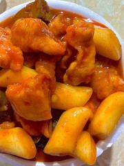 Spicy Korean tteokbokki with chewy rice cakes in a vibrant red sauce, topped with sesame seeds and green onions. A popular street food known for its addictive flavor and satisfying texture.