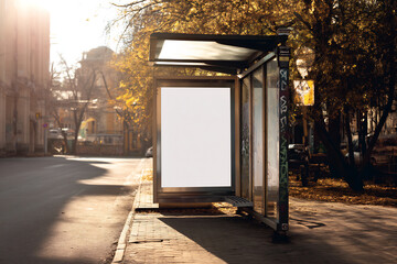 Bus Stop Poster Mockup. Vertical poster mockup at a glass bus stop on a quiet autumn street with warm lighting. Ideal for showcasing outdoor ads, promotions, or urban branding.