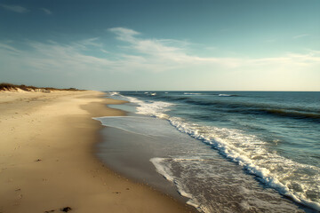 An empty beach with fine sand softly meets the ocean, as gentle waves rhythmically wash ashore, creating a tranquil atmosphere.