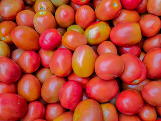 Background and texture close-up of large piles of tomatoes for sale at a traditional market