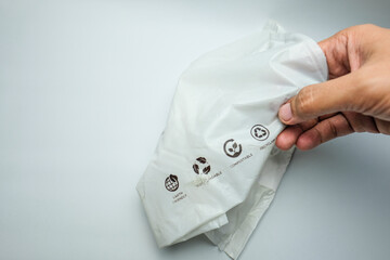 Hand Holding Biodegradable Plastic Bag with Eco-Friendly Symbols
