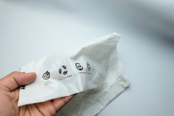 Hand Holding Biodegradable Plastic Bag with Eco-Friendly Symbols