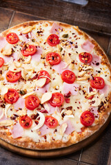Pizza with ham, cherry tomatoes and mozzarella cheese. Wooden background. Soft focus. Close up.	