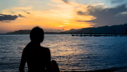 Silhouette of people by the Seaside at Sunset with a Pier in the Distance