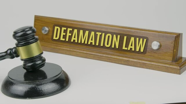 "Defamation law" text on a nameplate beside a gavel, symbolizing the legal framework that addresses false statements harming an individual's reputation