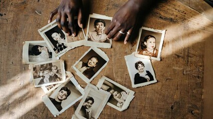 Nostalgic moments captured in vintage photographs on a wooden table with hands gently arranging them